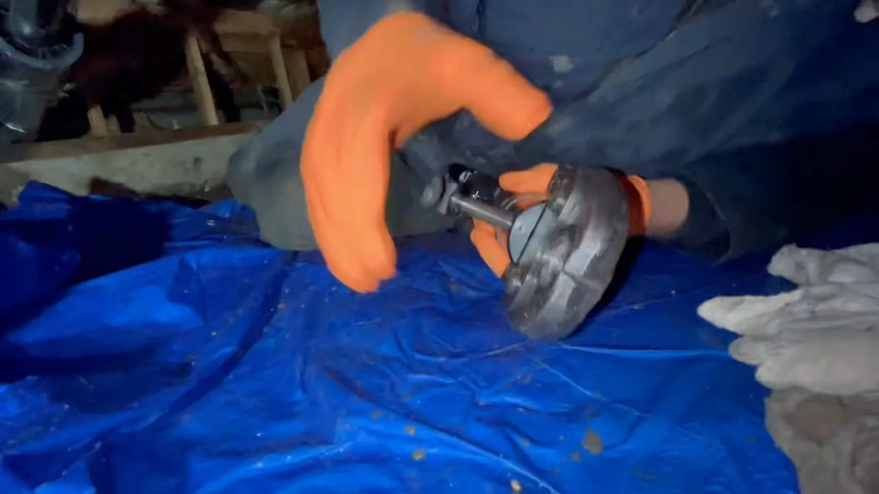 Worker using pipe cutter in crawlspace for a Sherman-area plumbing job